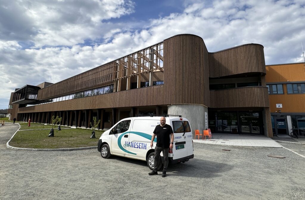 Rørlegger fra Haneseth VVS Bodø AS står foran nyåpnede Bodø Spektrum, med konkurransebasseng og rustfrie renner og sluk fra Purus